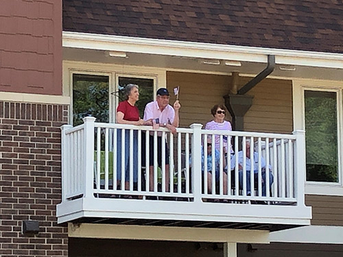 Wildly waving Old Glory from his Watertower Square balcony is Mayflower resident, Stan Greenwald, with wife Gail. Residents Seymour and Carmen Raffety are seated behind the railing with Marie Eisenman standing behind them.